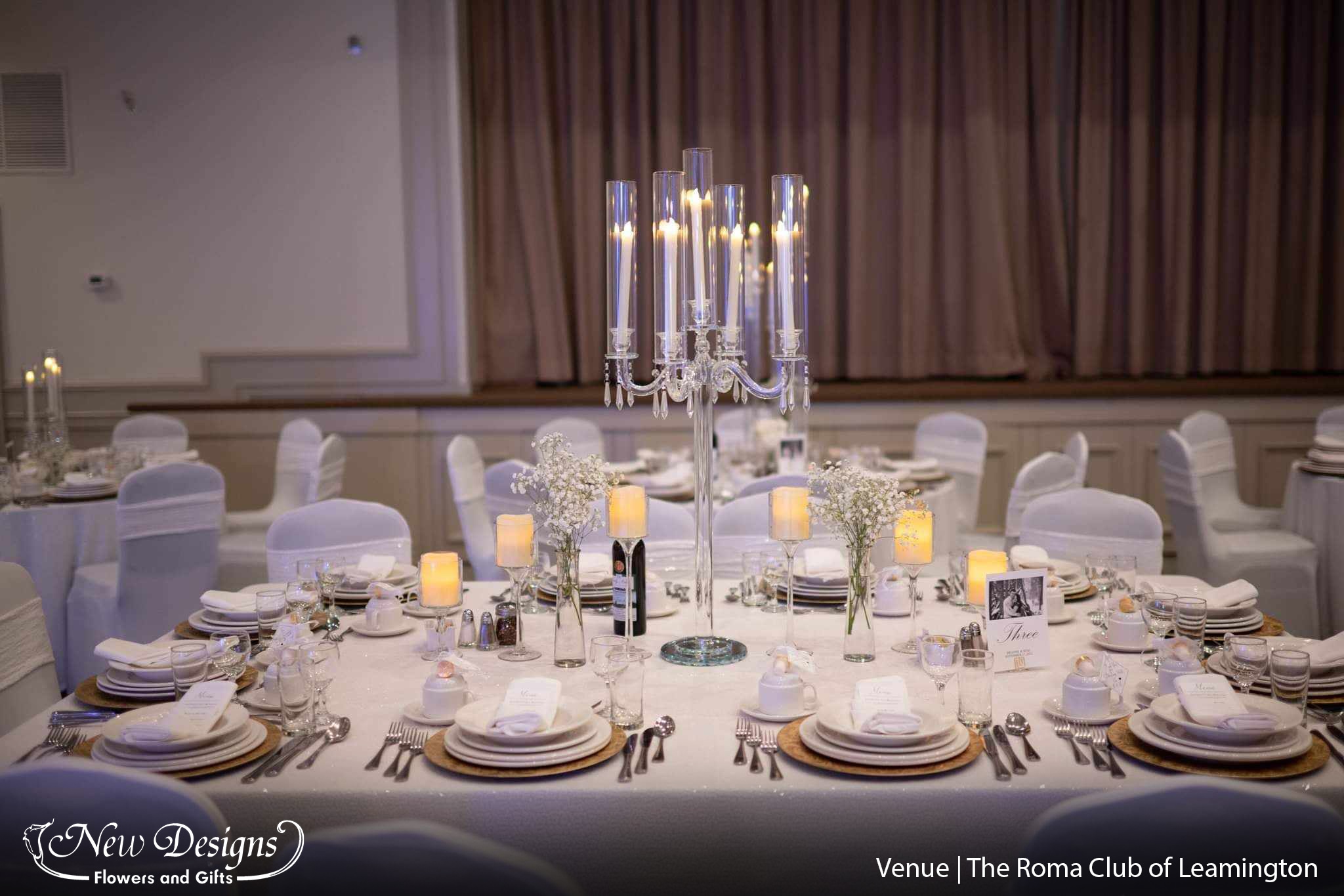 A stunning glass candelabra is offset on either side by 3 Goblets in descending sizes sporting a pillar candle each.